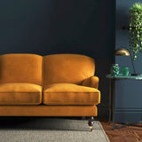 Sofa covered in a orange velvet upholstery fabric