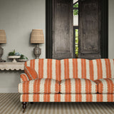 Sofa upholstered in a printed linen fabric in orange and off white, featuring a striped fern design.