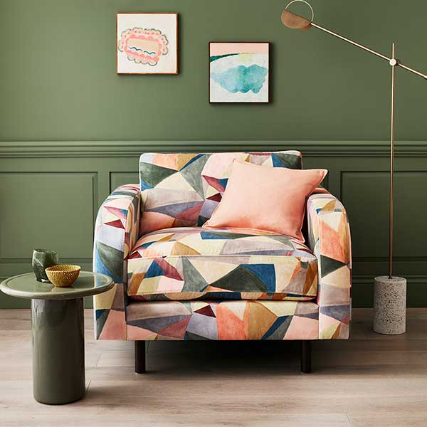 Statement armchair upholstered in Crystal Sunset Velvet, featuring abstract geometric patterns in peach, mauve, and sky blue, adding a bold pastel touch.