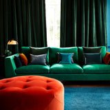 Sofa covered in green velvet upholstery fabric and footstall in orange velvet upholstery fabric