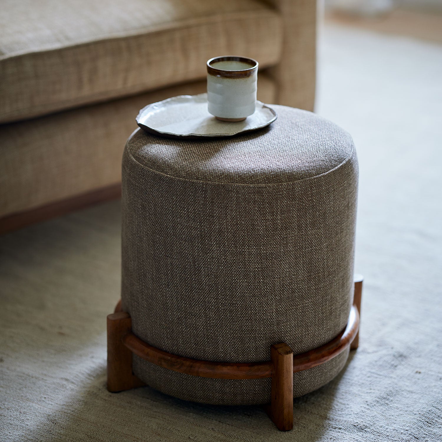 Brown footstool upholstered in a chenille woven fabric.