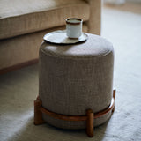 Brown footstool upholstered in a chenille woven fabric.